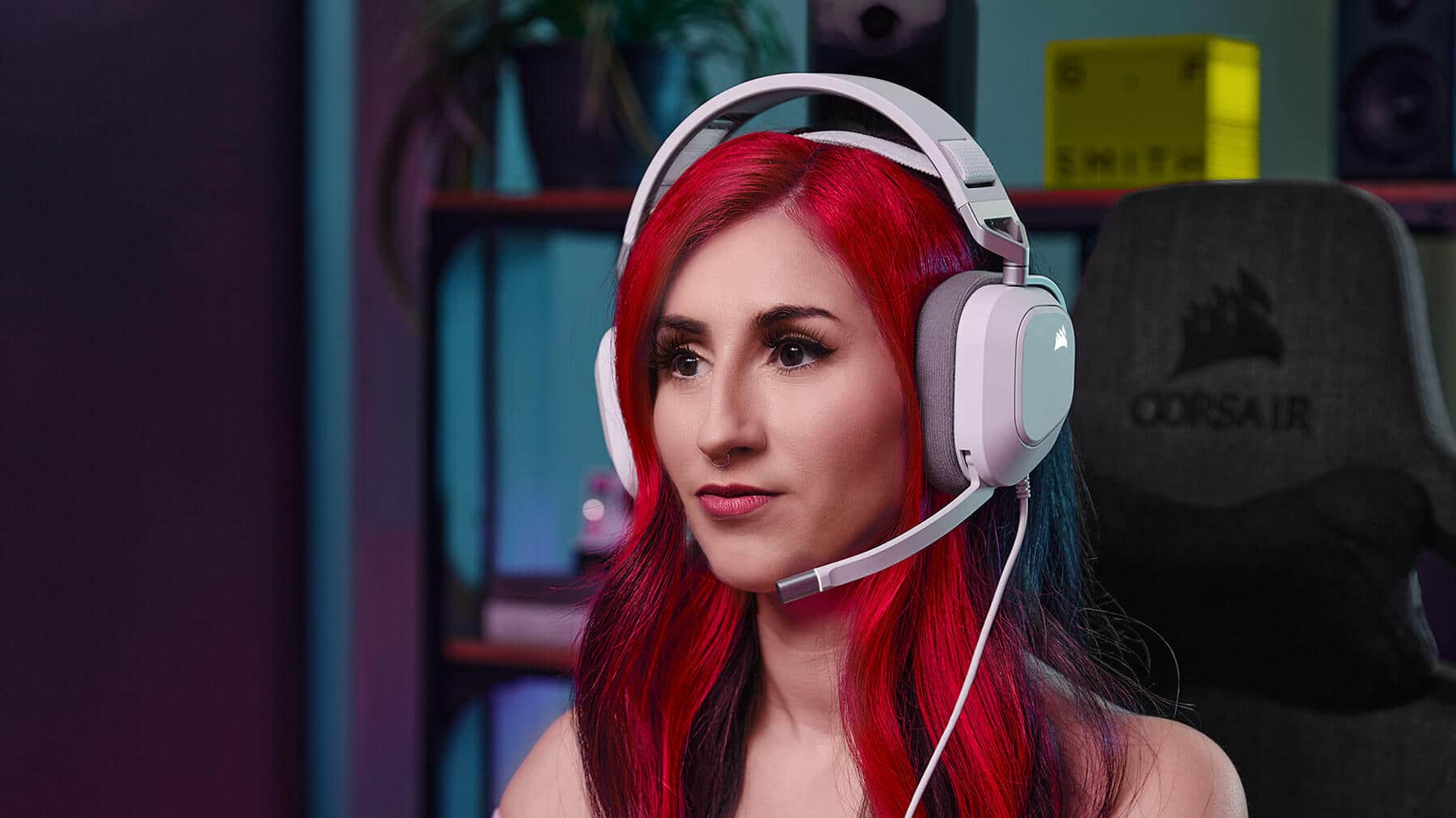 Mujer con el pelo recogido mirando directamente al frente con los auriculares HS80 RGB USB y mostrando el cómodo diseño de la diadema flotante. 