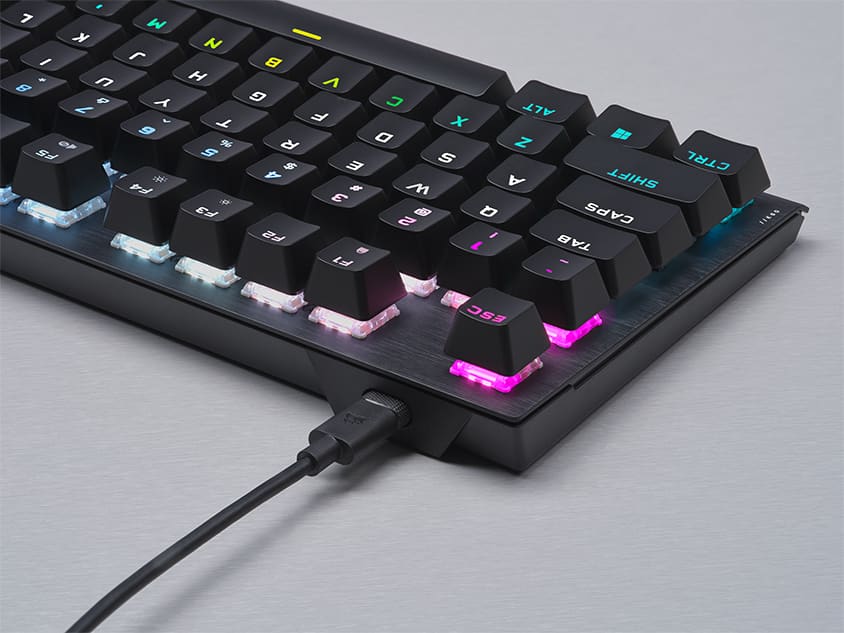 Close up top down shot of K60 PRO TKL from the topside, looking at the side with the detachable USB Type-C Cable and the RGB lighting being displayed.